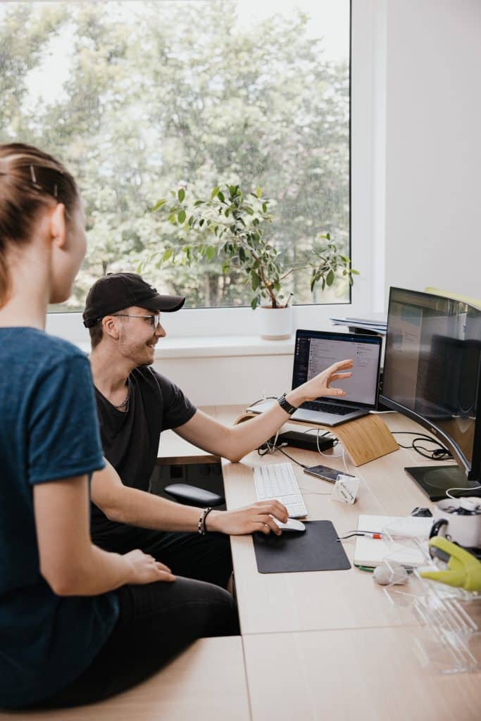 Zwei Personen sehen auf einen PC und sind begeistert von der Online-Sichtbarkeit durch SEO einer Website einer Website