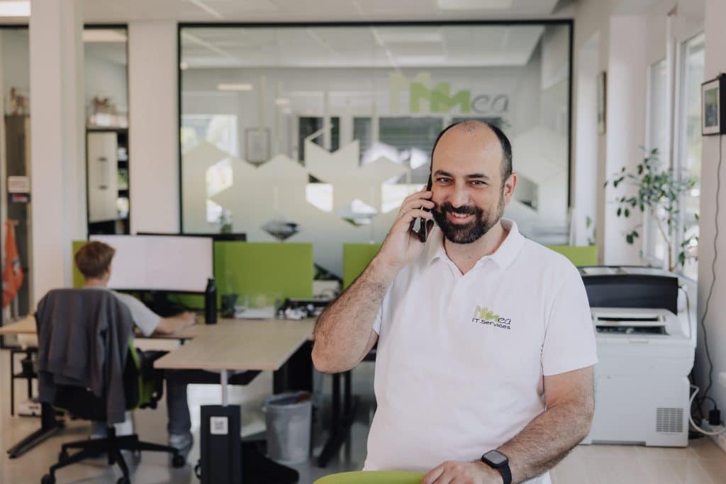 Michael Ulm telefoniert stehend im Büro und stützt sich mit der Hand auf einem Sesselrücken ab