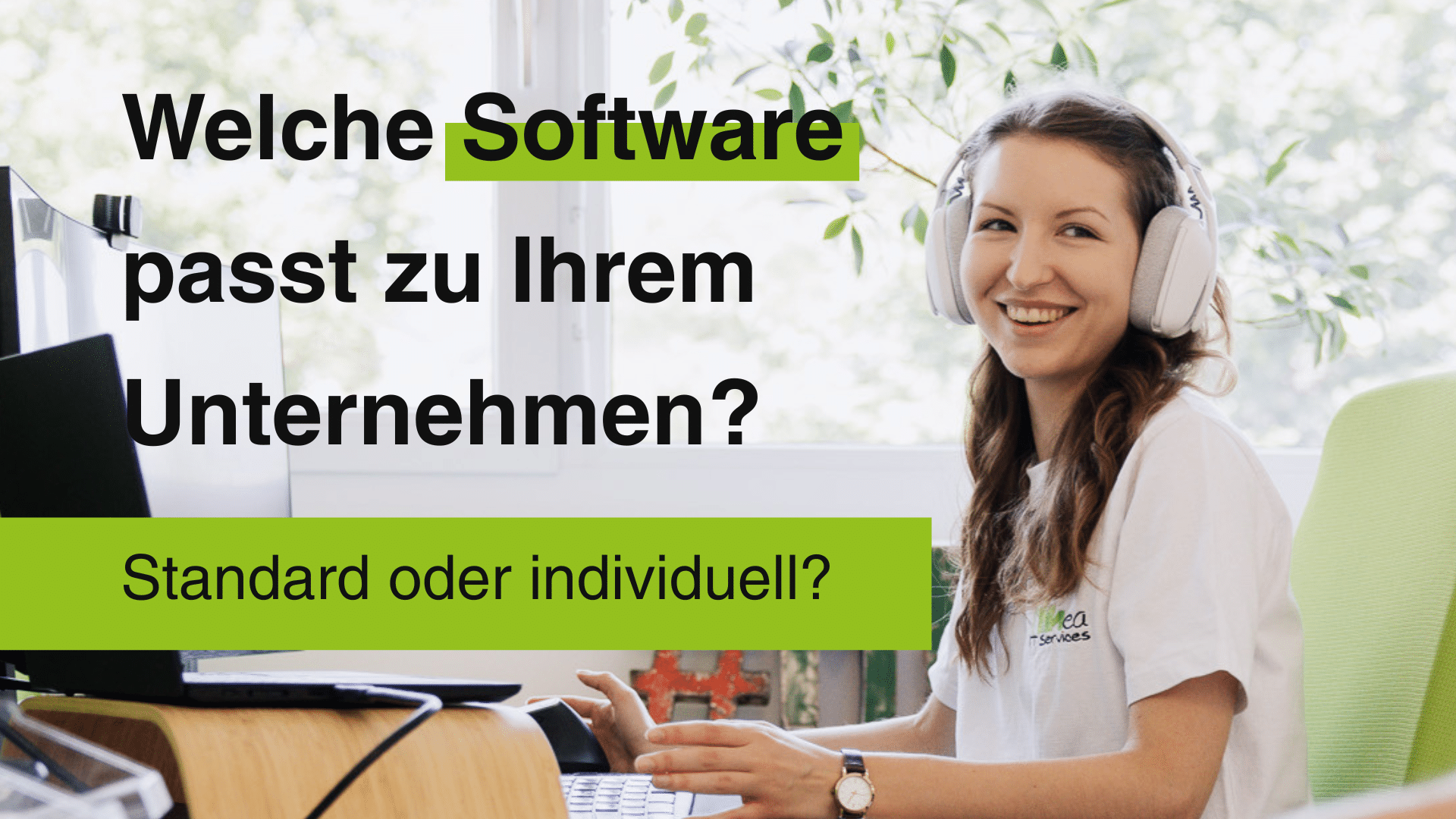 Eine Frau mit weißen Kopfhörern sitzt am Schreibtisch vor Tastatur und Bildschirm und sieht lachend zur Seite. Auf dem Bild steht: Welche Software passt zu Ihrem Unternehmen? Standard oder individuell?